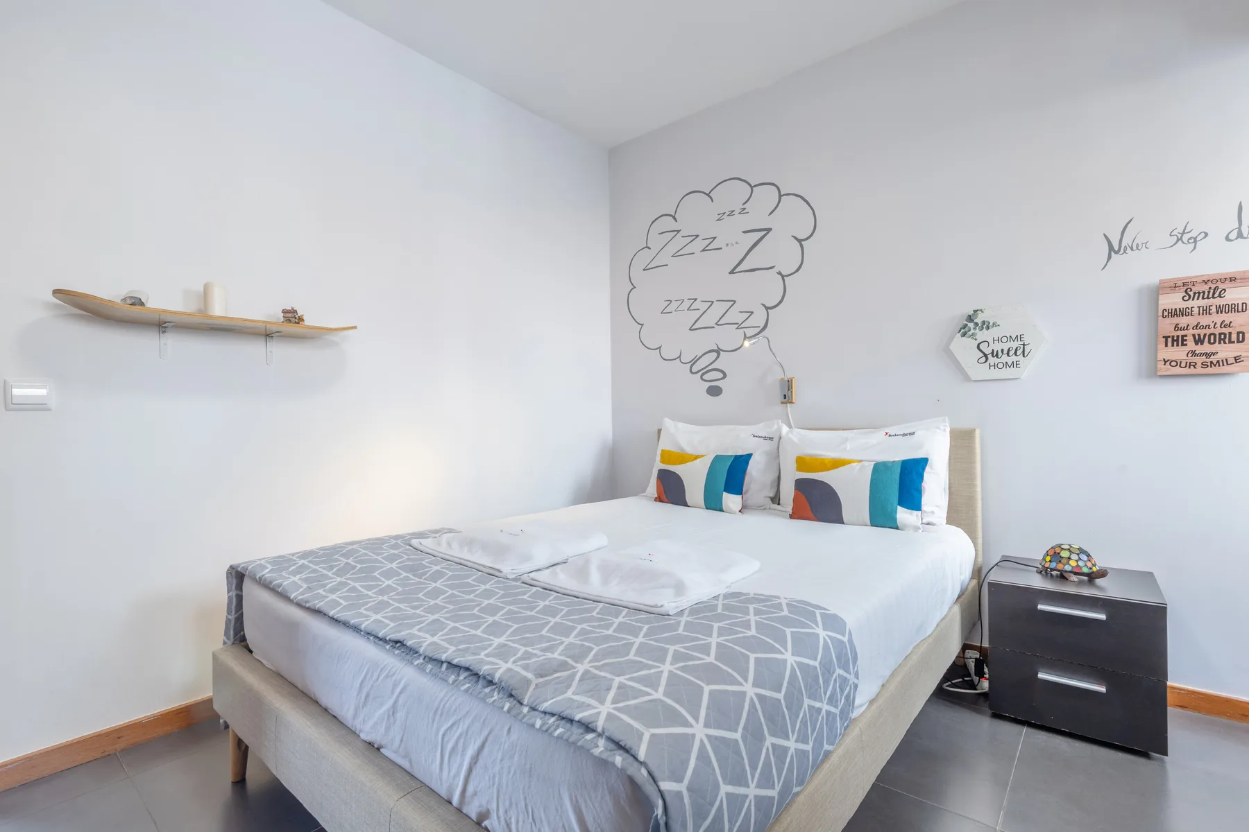A bedroom with a neatly made bed and colorful pillows.