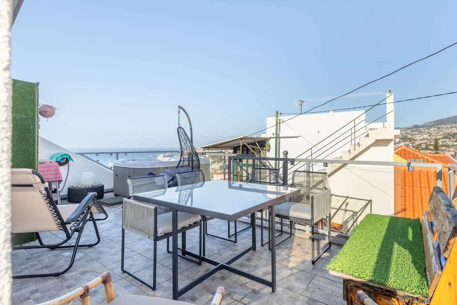 Outdoor terrace with a dining table and seating overlooking the sea.
