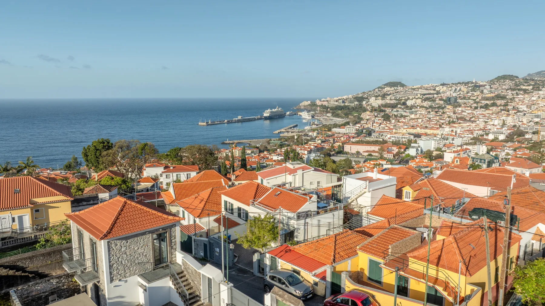 A hillside coastal city with red-tiled rooftops overlooking the sea.