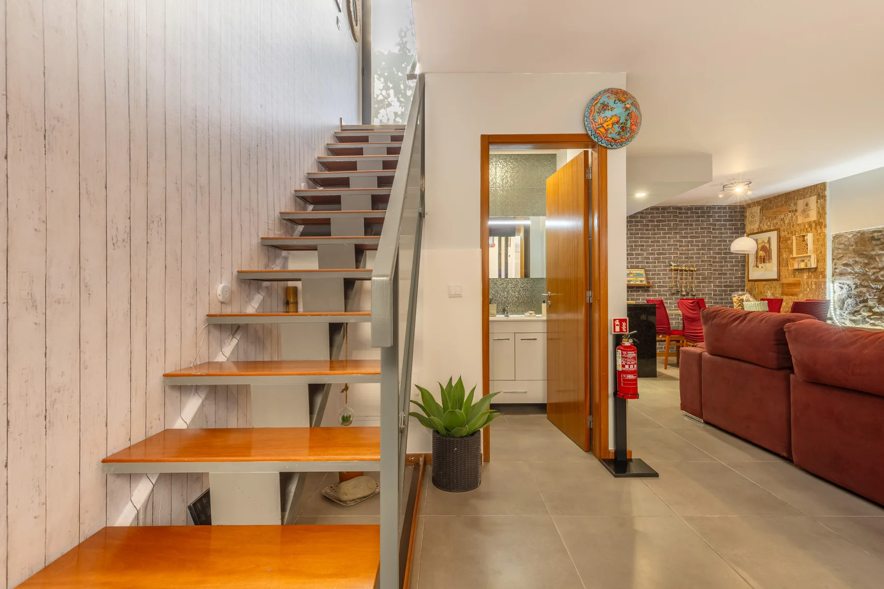 An open staircase beside a kitchen and living area with seating.