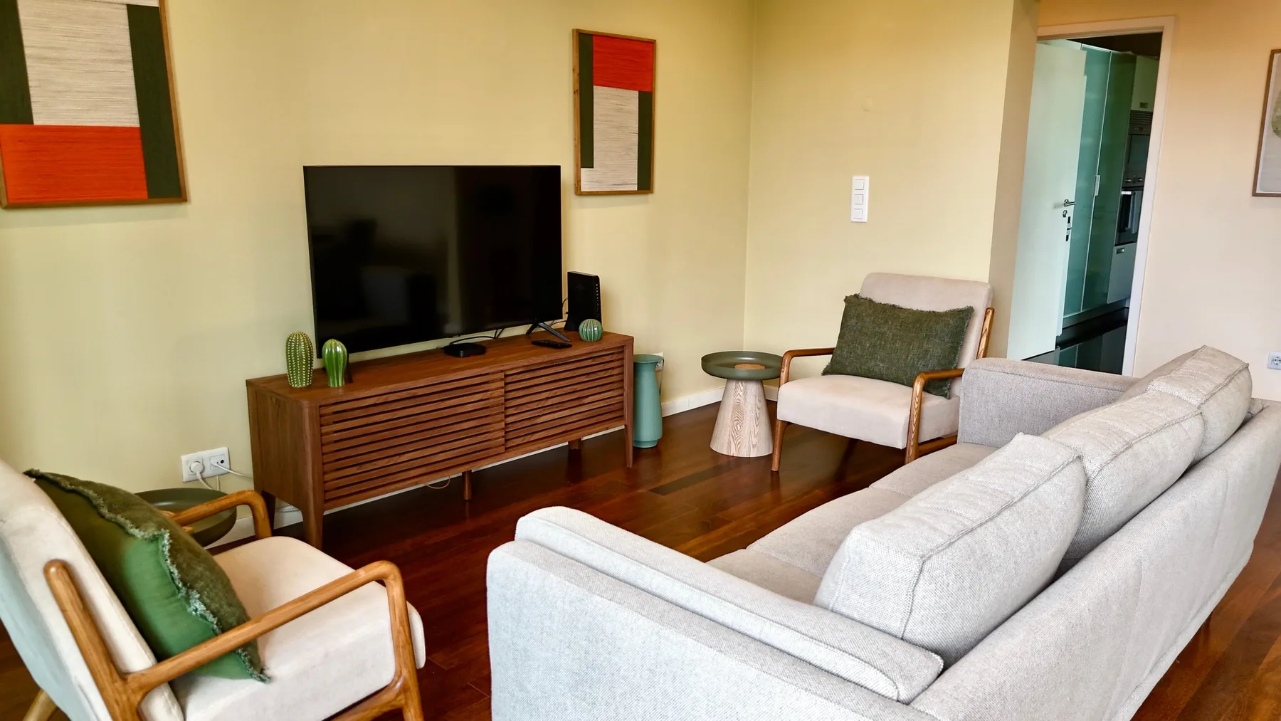 Una sala de estar con asientos dispuestos alrededor de un televisor y un mueble de madera.