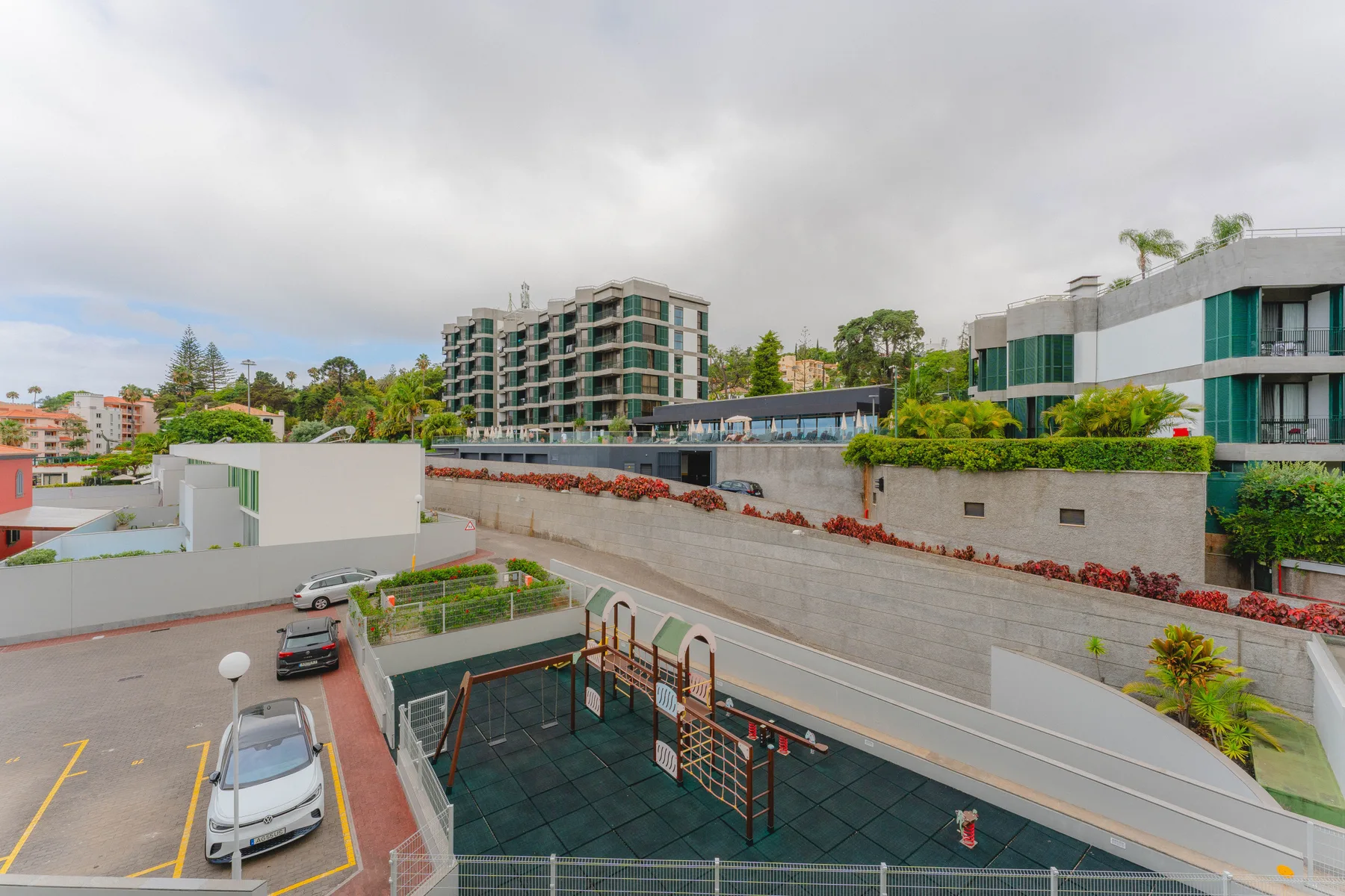 Un complejo de apartamentos moderno da a un patio pavimentado y edificios cercanos.
