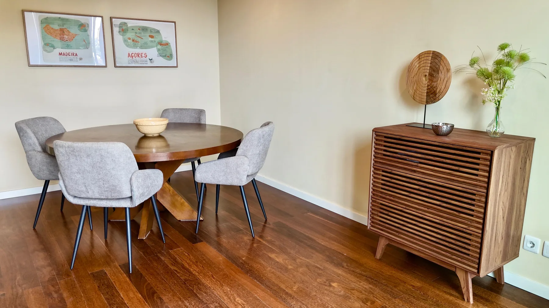 Comedor con una mesa redonda, asientos tapizados y un mueble de madera.