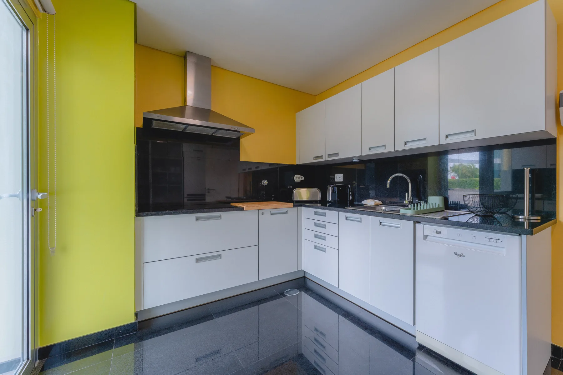 Una cocina moderna con armarios blancos y encimeras oscuras.