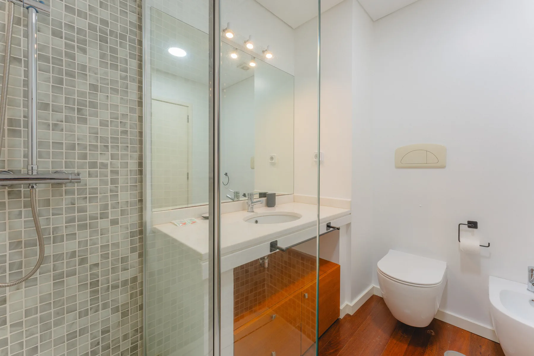 Un baño con ducha de vidrio, lavabo y inodoro.