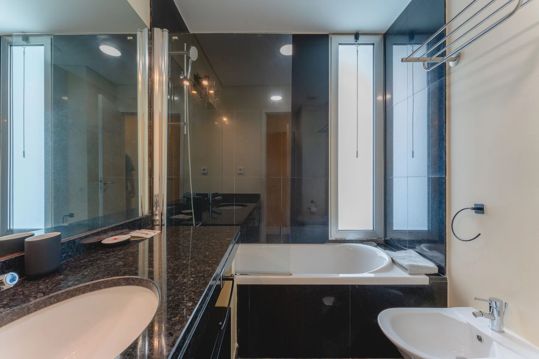 Un baño con bañera, mampara de ducha de vidrio y lavabo.