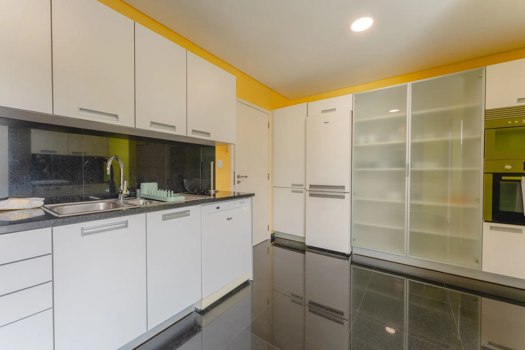 Una cocina moderna con gabinetes blancos, un fregadero y electrodomésticos integrados.