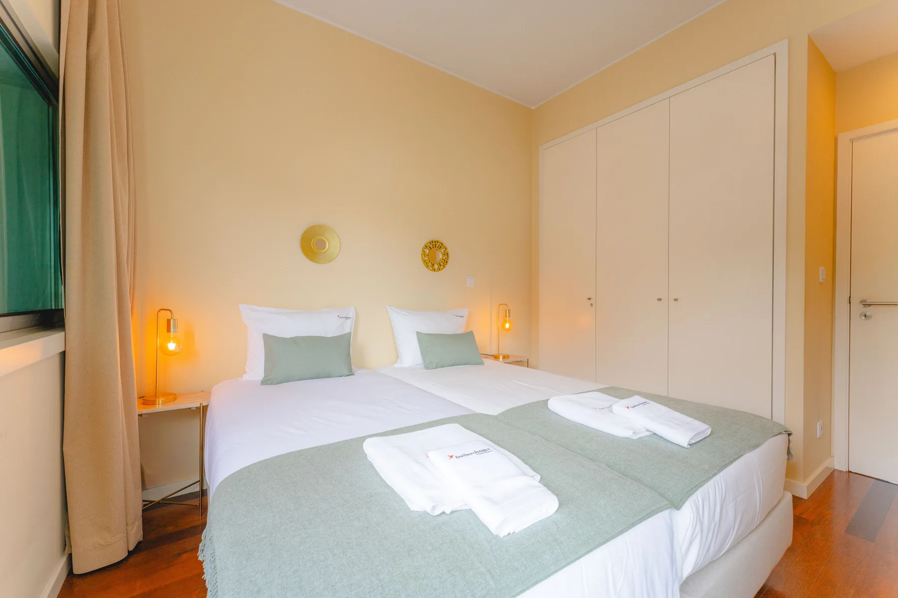 Un dormitorio con dos camas, ropa de cama blanca y lámparas de noche.