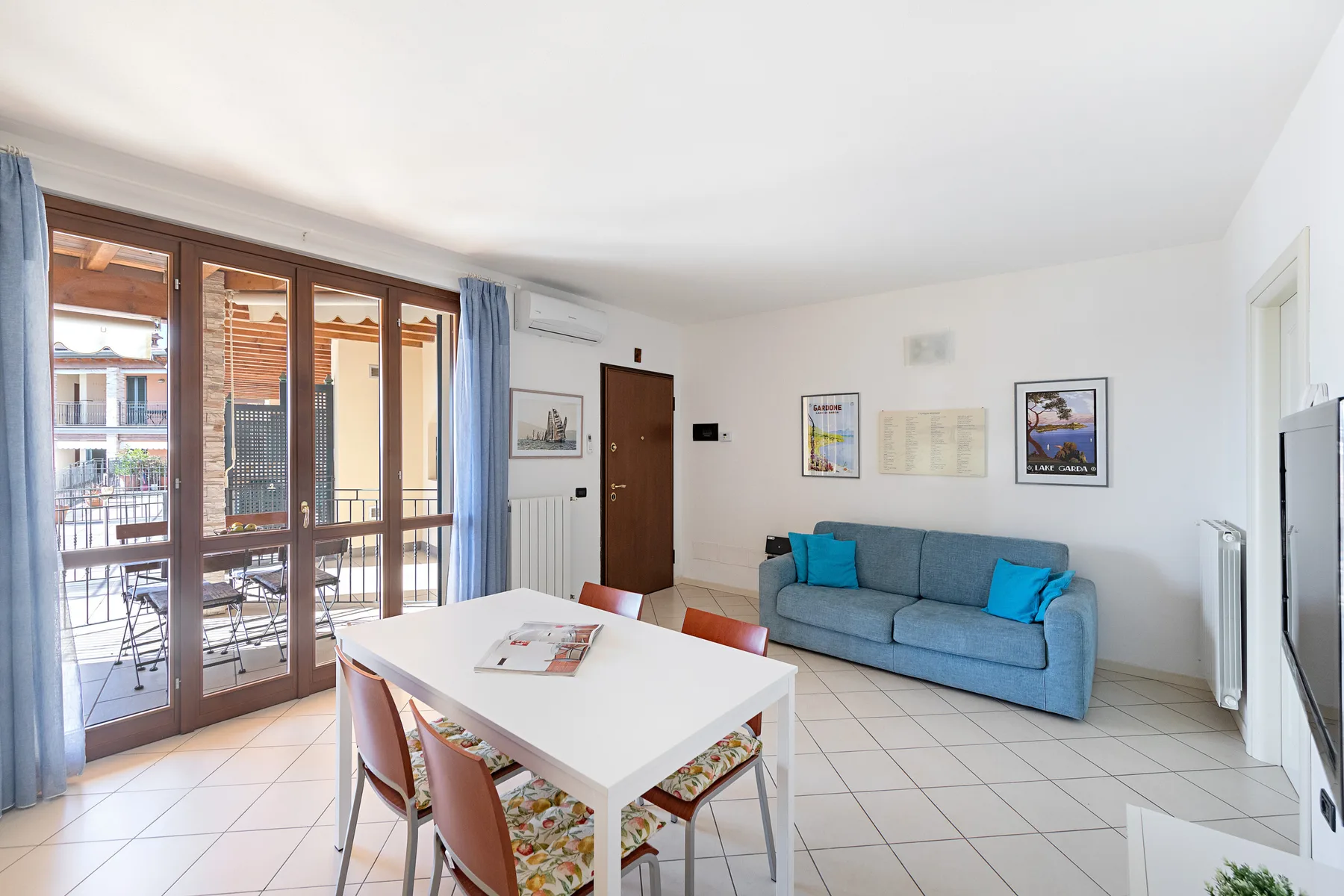 A bright living and dining area with blue seating beside large glass doors.