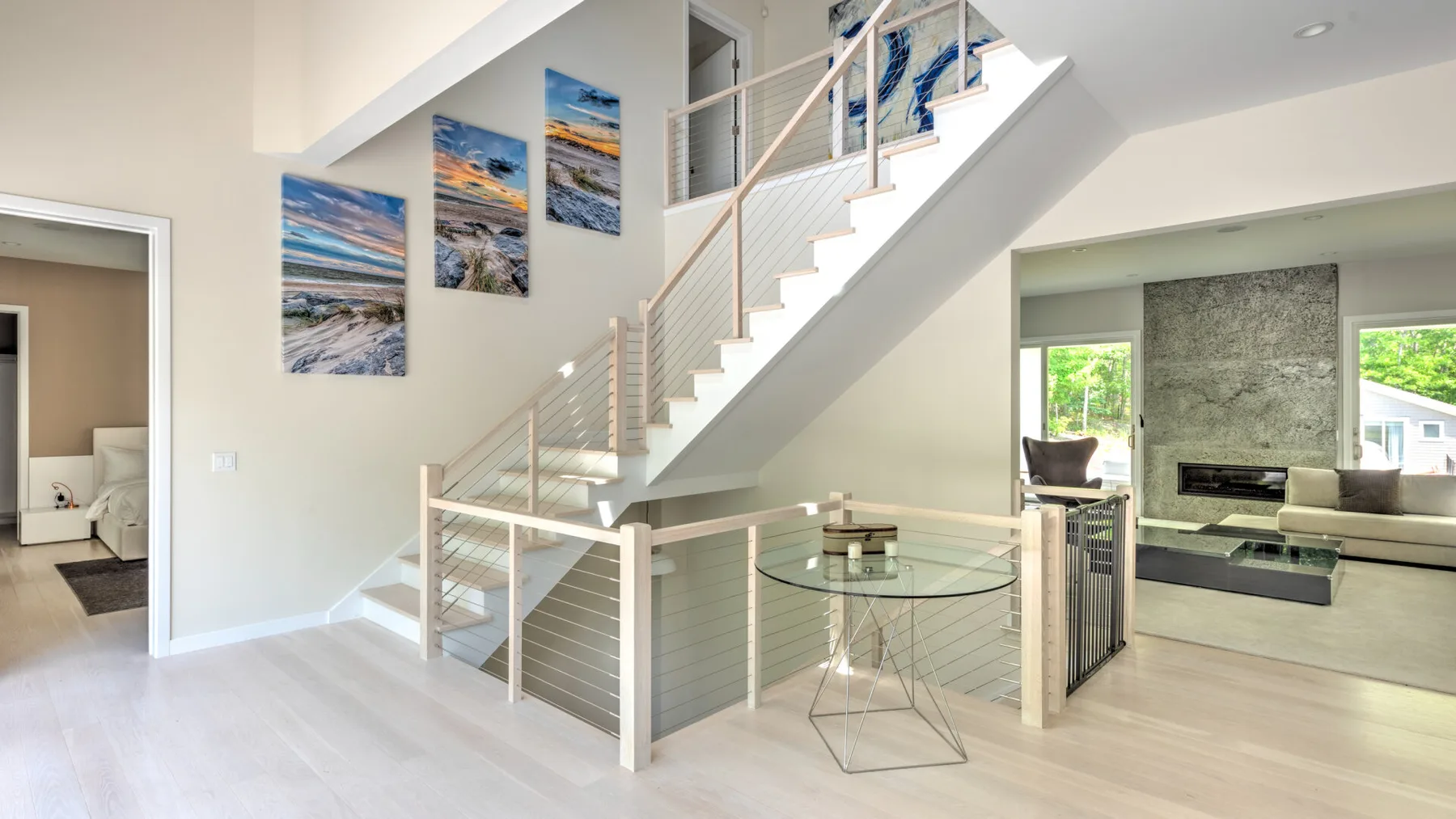 Una luminosa sala de estar con una escalera y una mesa de comedor de vidrio.