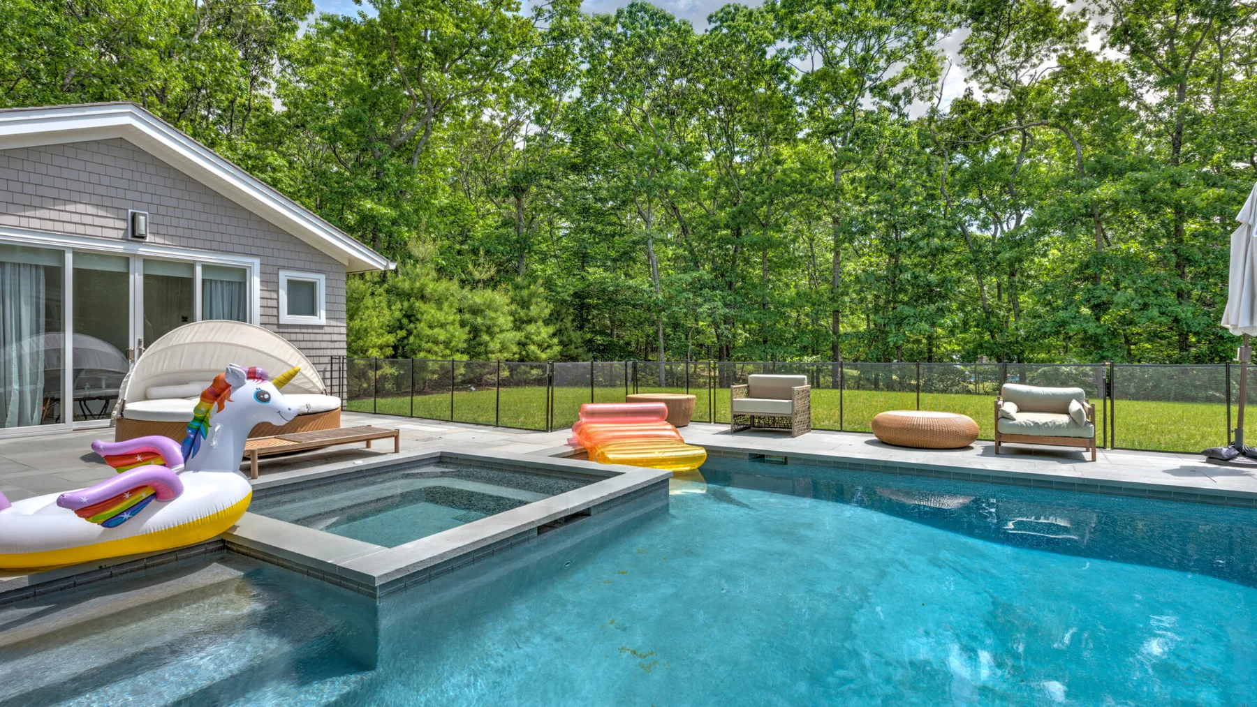 Una piscina al aire libre con un jacuzzi elevado y asientos para descansar.