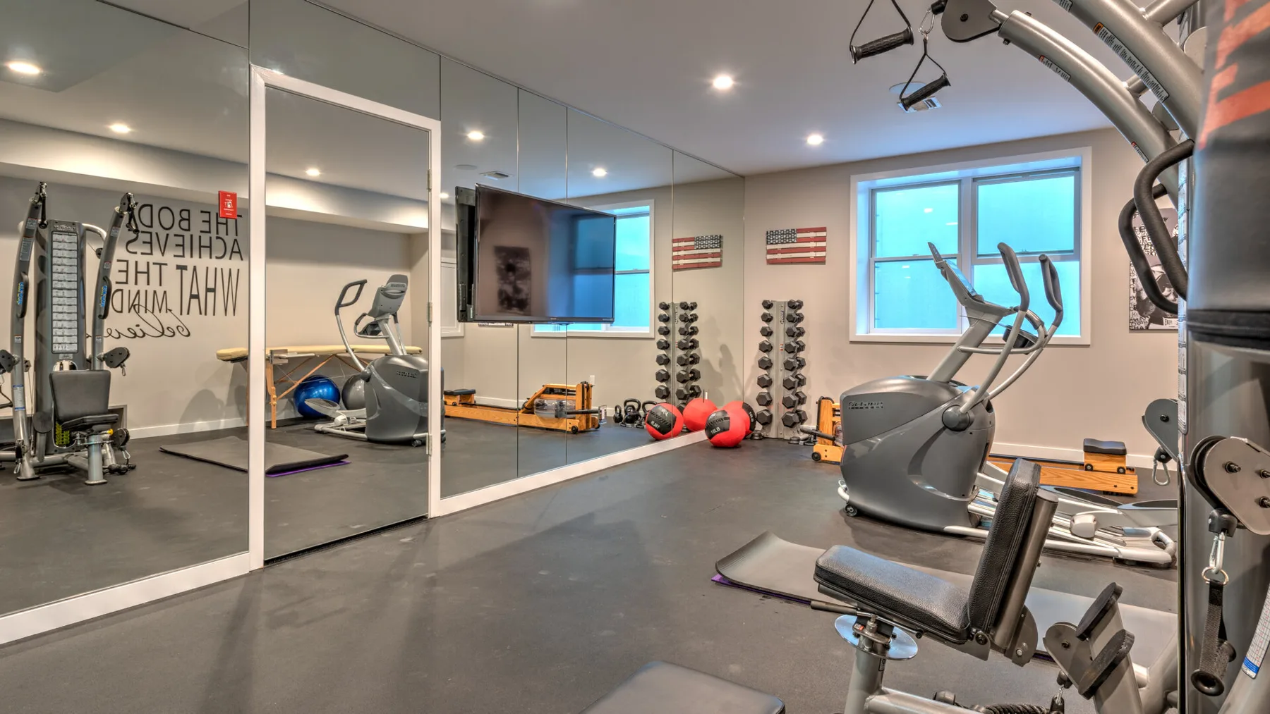 Un gimnasio con máquinas de ejercicio, pesas y paredes con espejos.