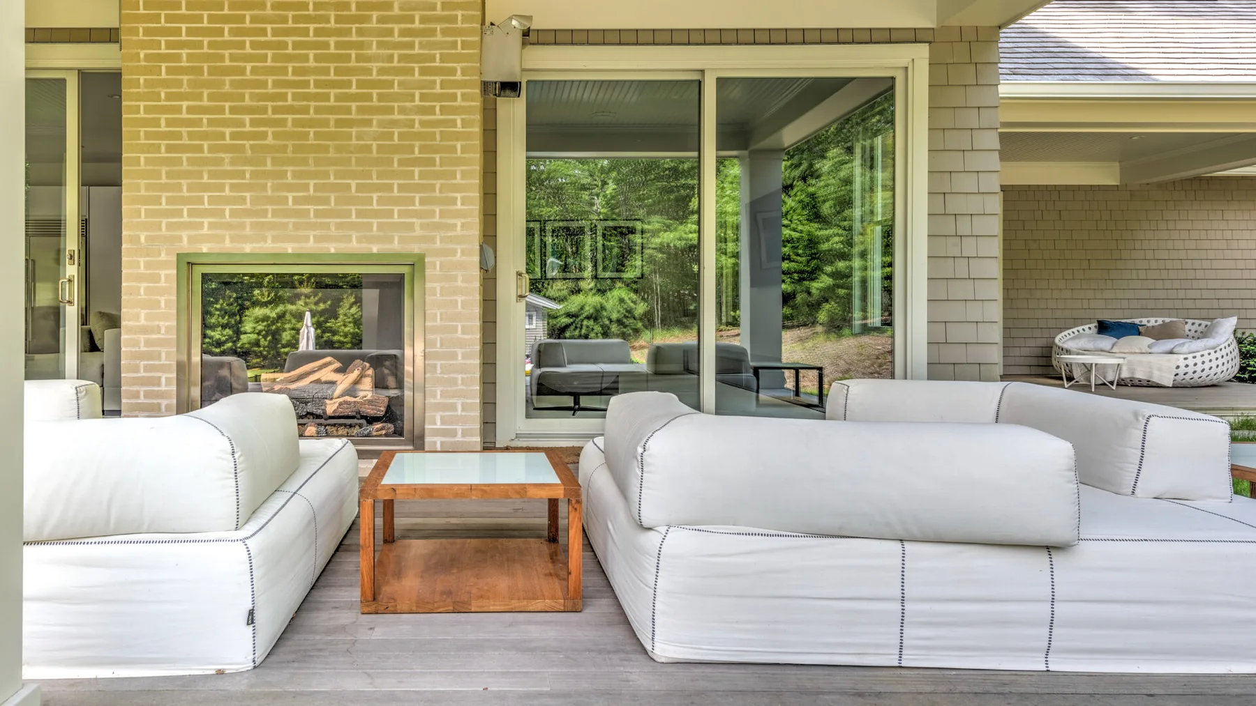 Una zona de estar exterior cubierta con sofás blancos y una mesa baja de madera.