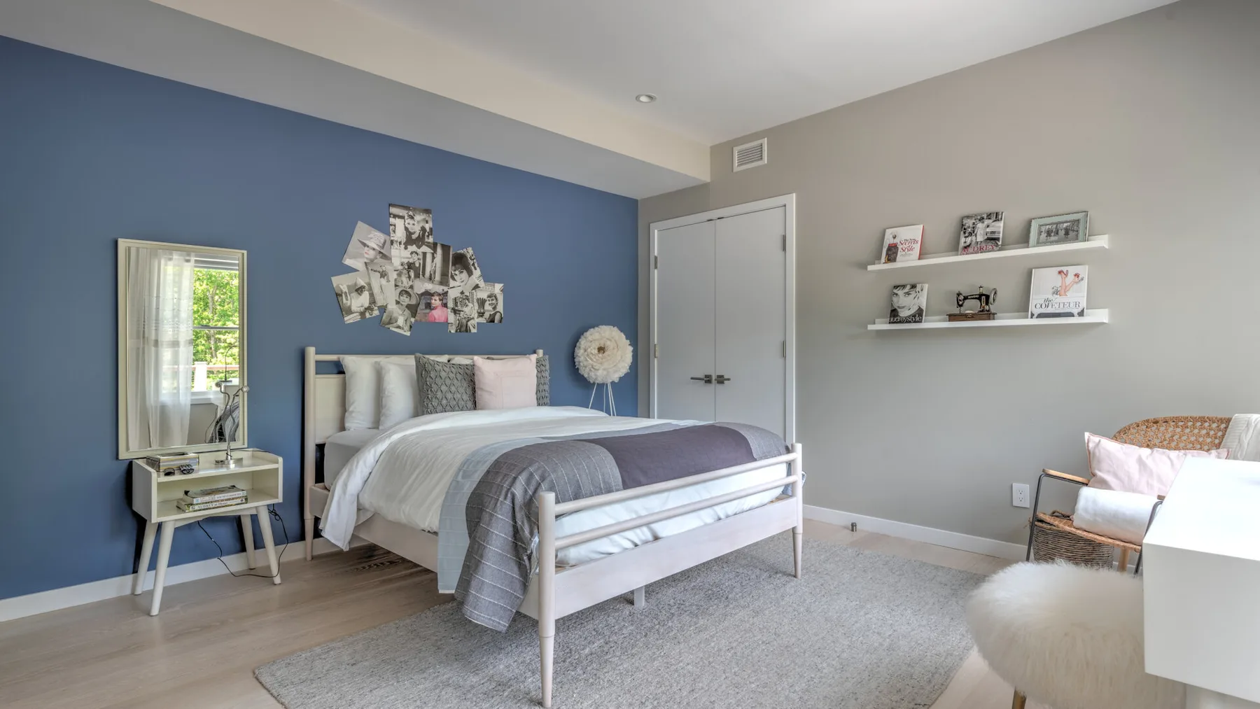 Un dormitorio con una cama junto a una pared azul y una alfombra clara.