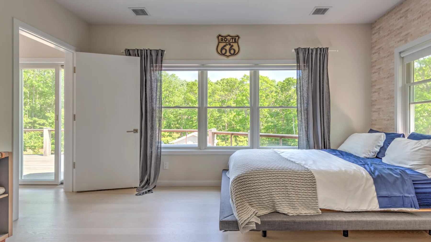 Un dormitorio con una cama junto a grandes ventanas con vistas a la vegetación.