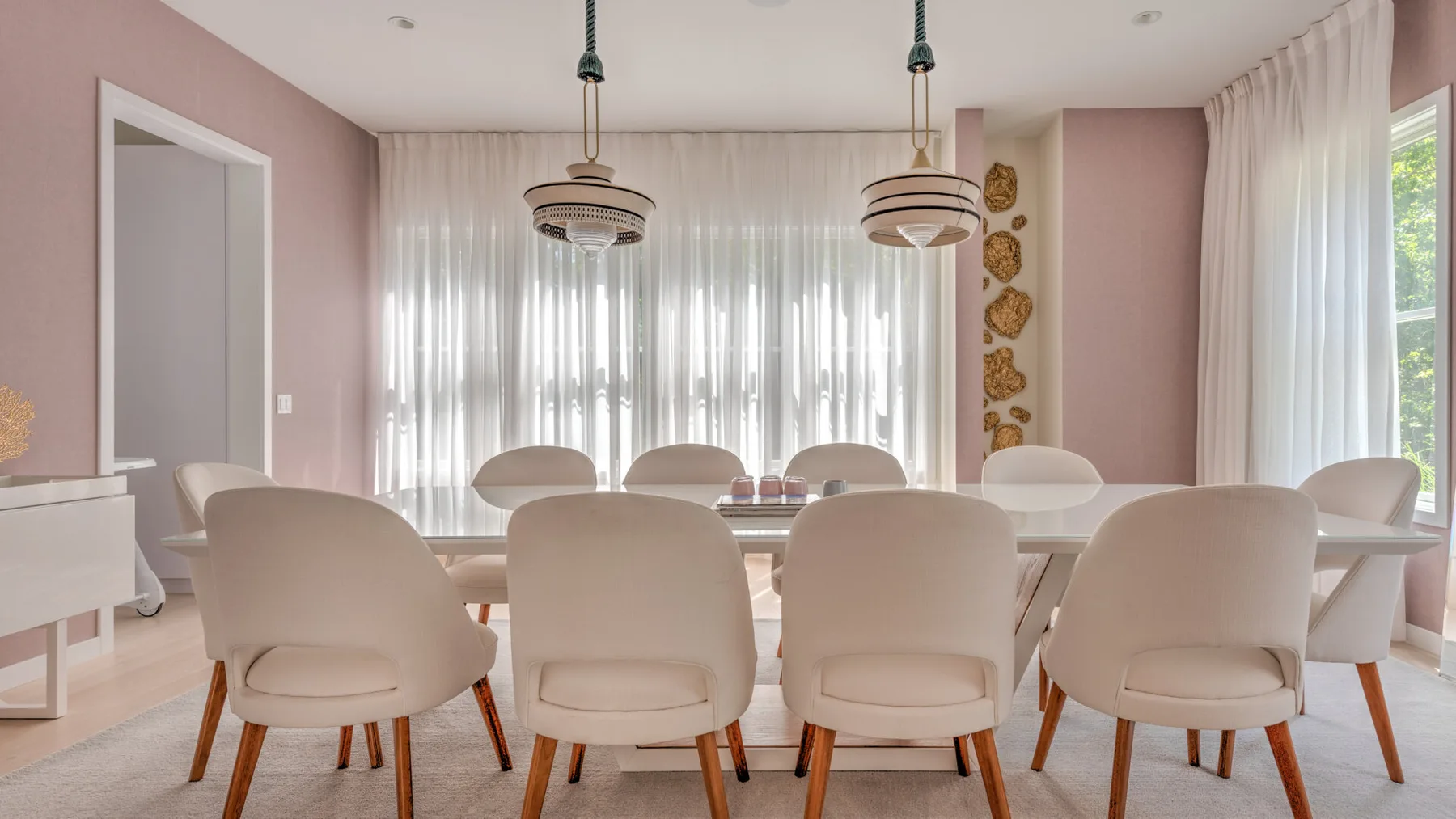 Un comedor con una mesa larga y asientos tapizados bajo lámparas colgantes.