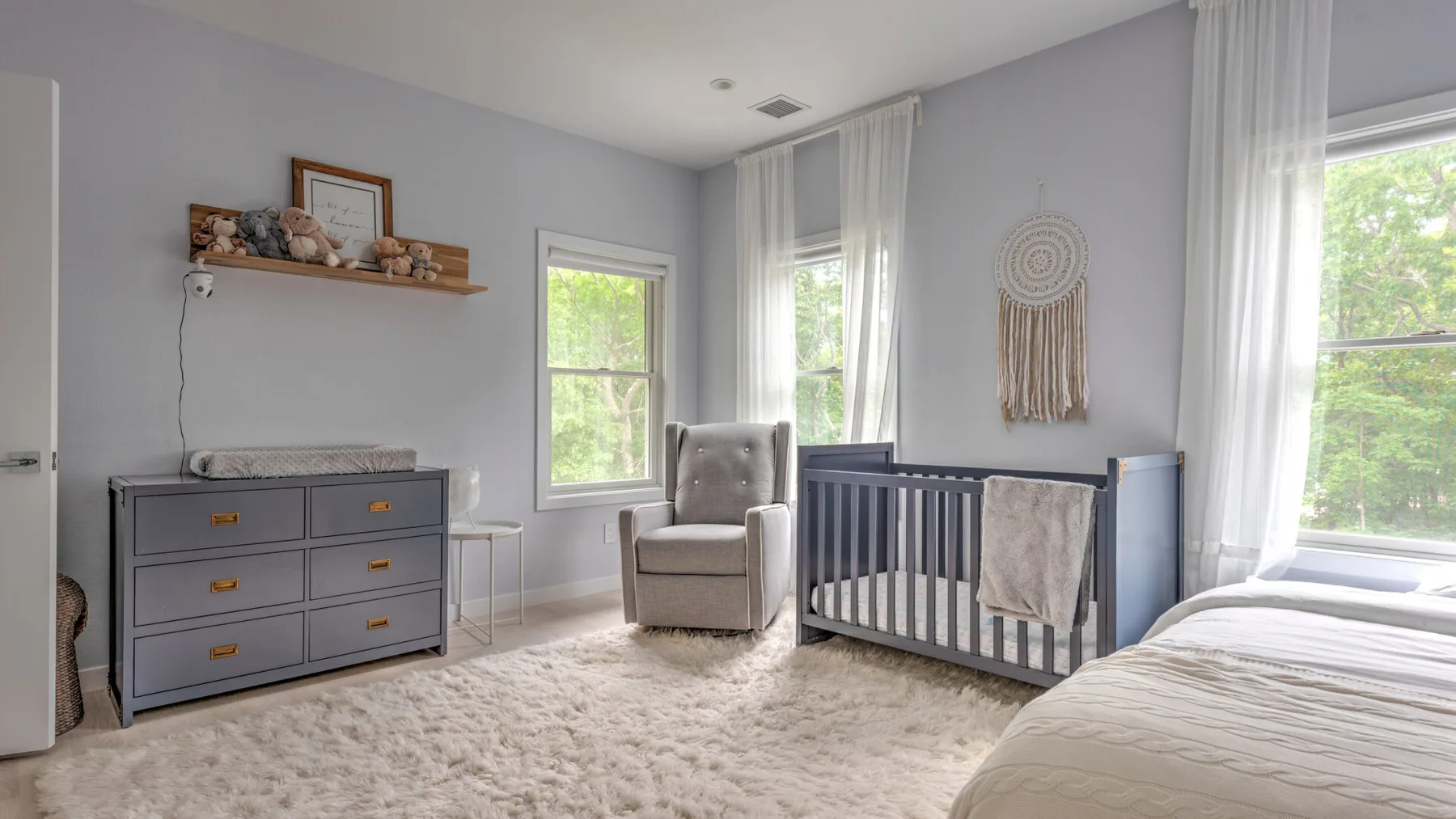 Un cuarto infantil luminoso con una cuna, un sillón y una cómoda.