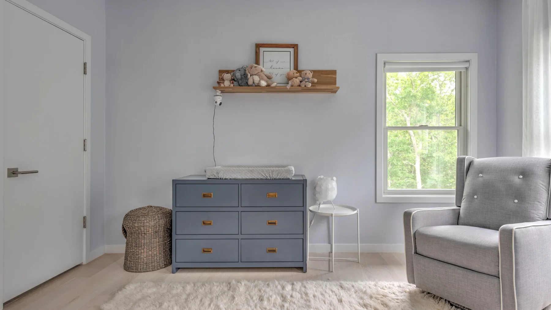 Un dormitorio luminoso con una cómoda, un sillón acolchado y una ventana.