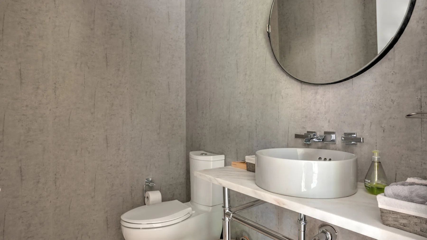 Un lavabo de baño con una pila blanca, un espejo de pared y un inodoro.