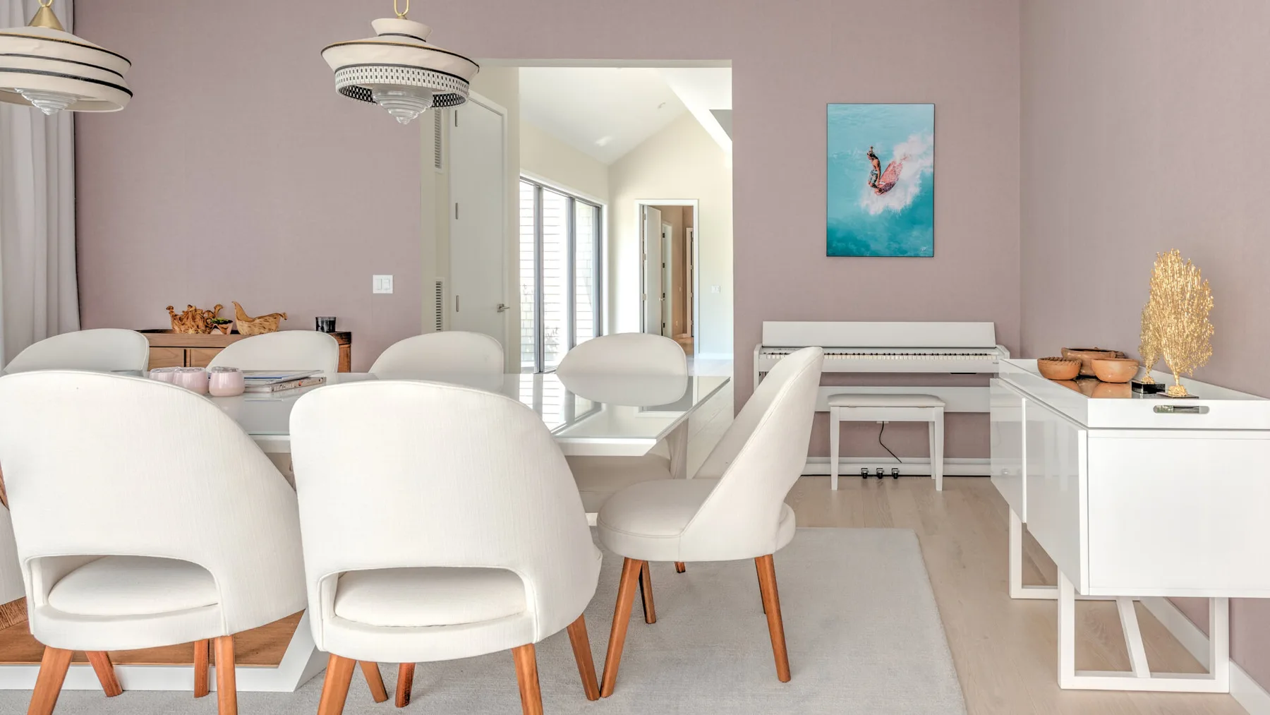Un comedor luminoso con asientos blancos, una mesa y un piano junto a la pared.