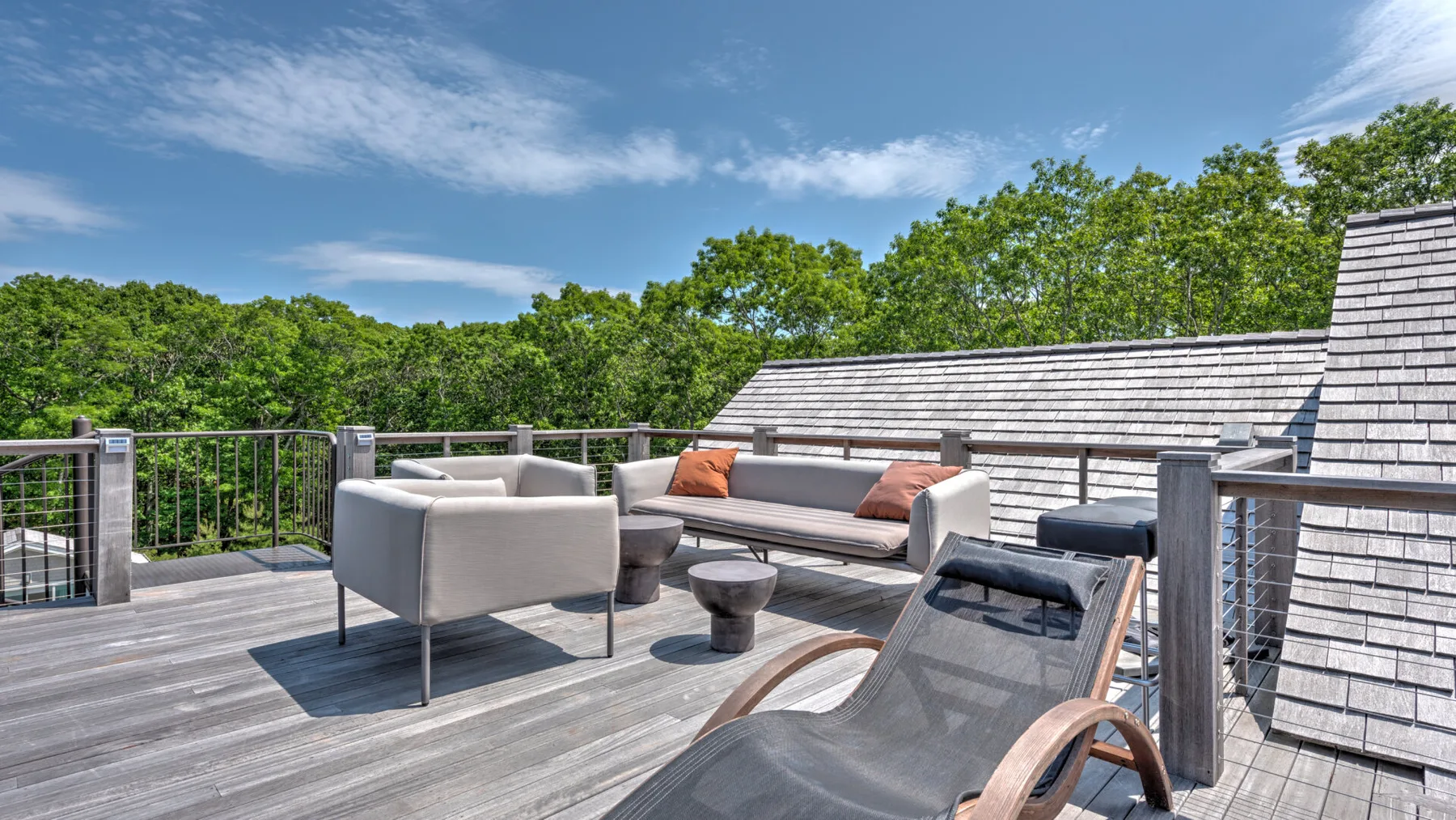 Una terraza exterior tiene asientos de descanso y vistas a los árboles cercanos.