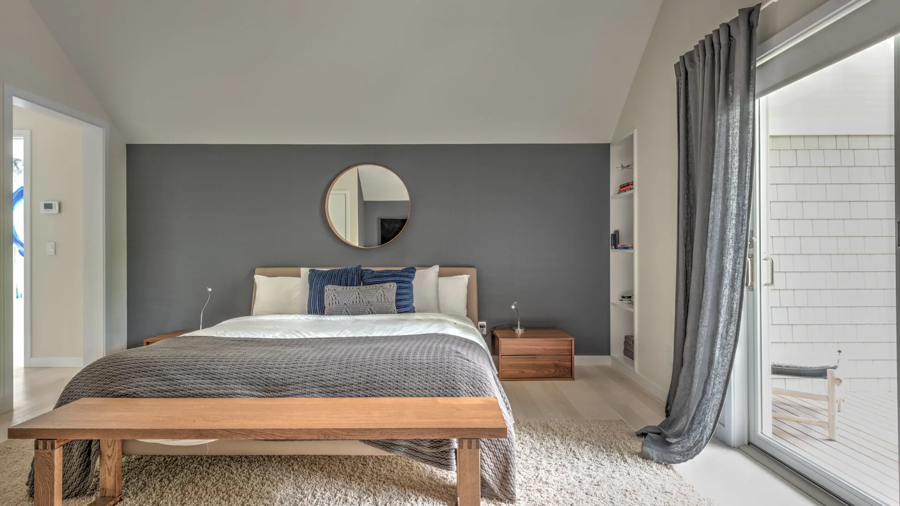 Un dormitorio con una cama bien tendida y una pared de acento gris.