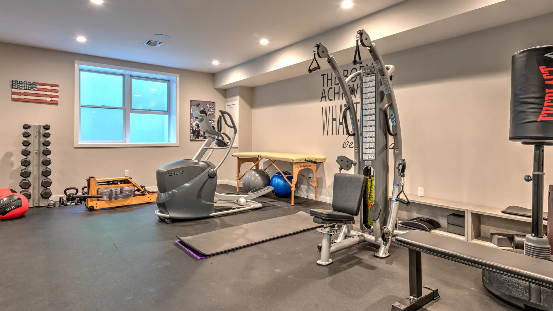 Un gimnasio en casa con equipo de ejercicio, pesas y una ventana grande.