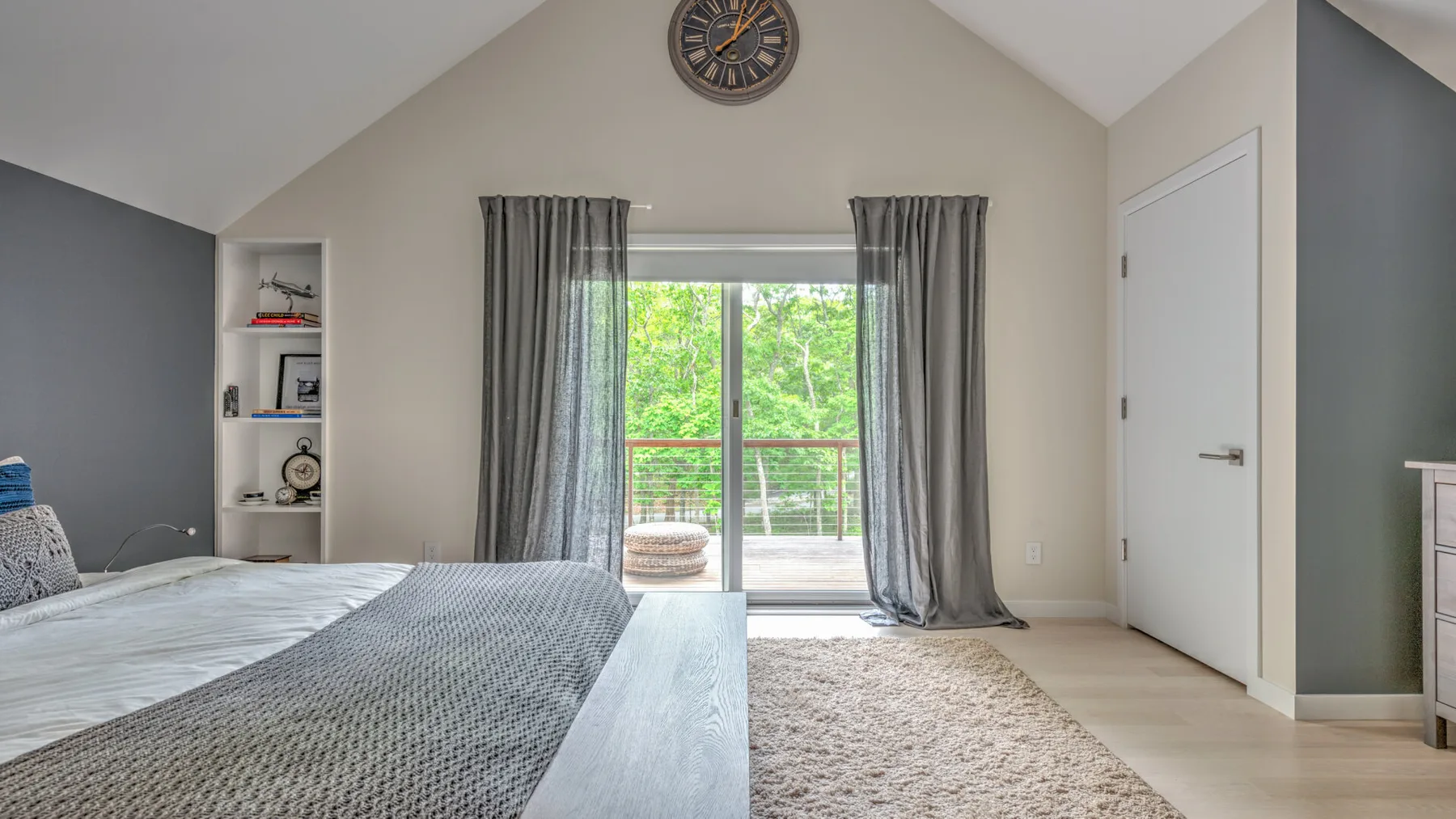 Un dormitorio con una cama, una ventana con cortinas y una alfombra clara.
