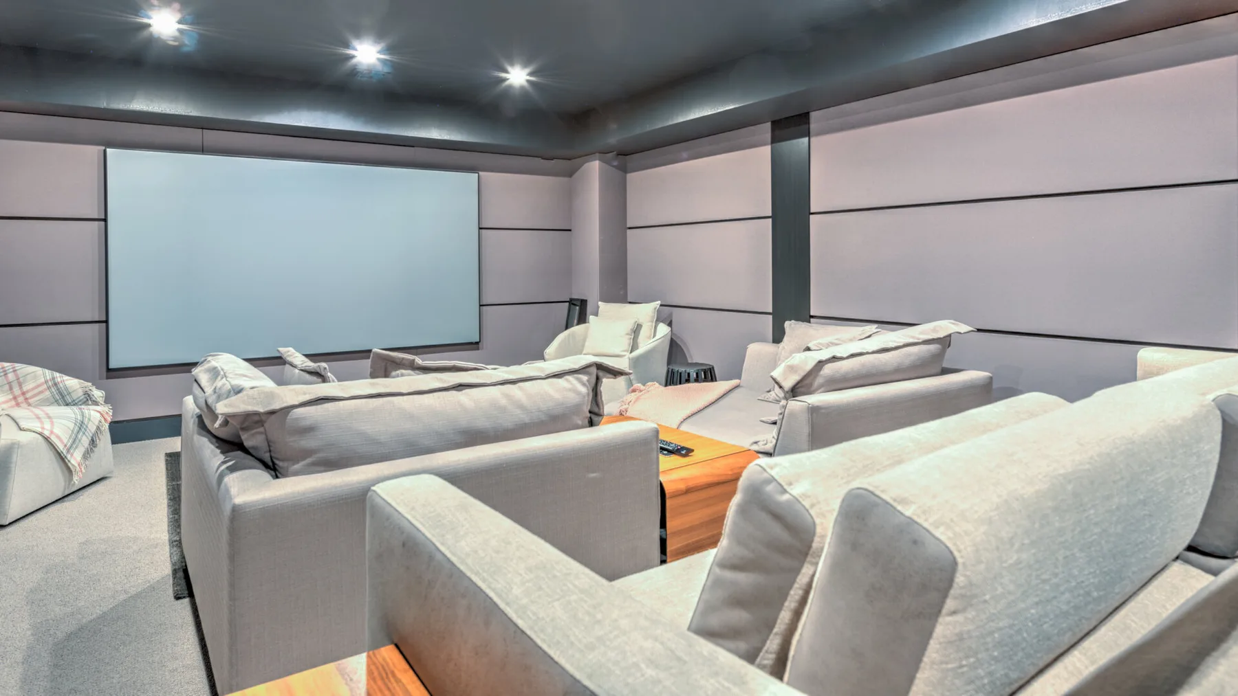 A lounge with rows of seating facing a large wall-mounted screen.