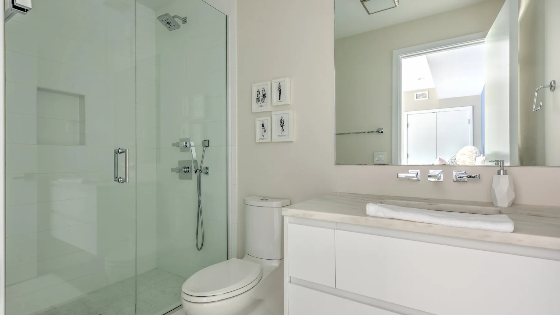 Un baño luminoso con ducha de vidrio, inodoro y un amplio tocador.