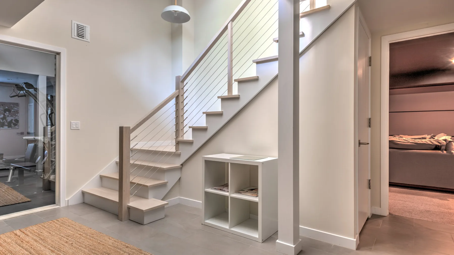 Una escalera interior con un pequeño estante abierto debajo.