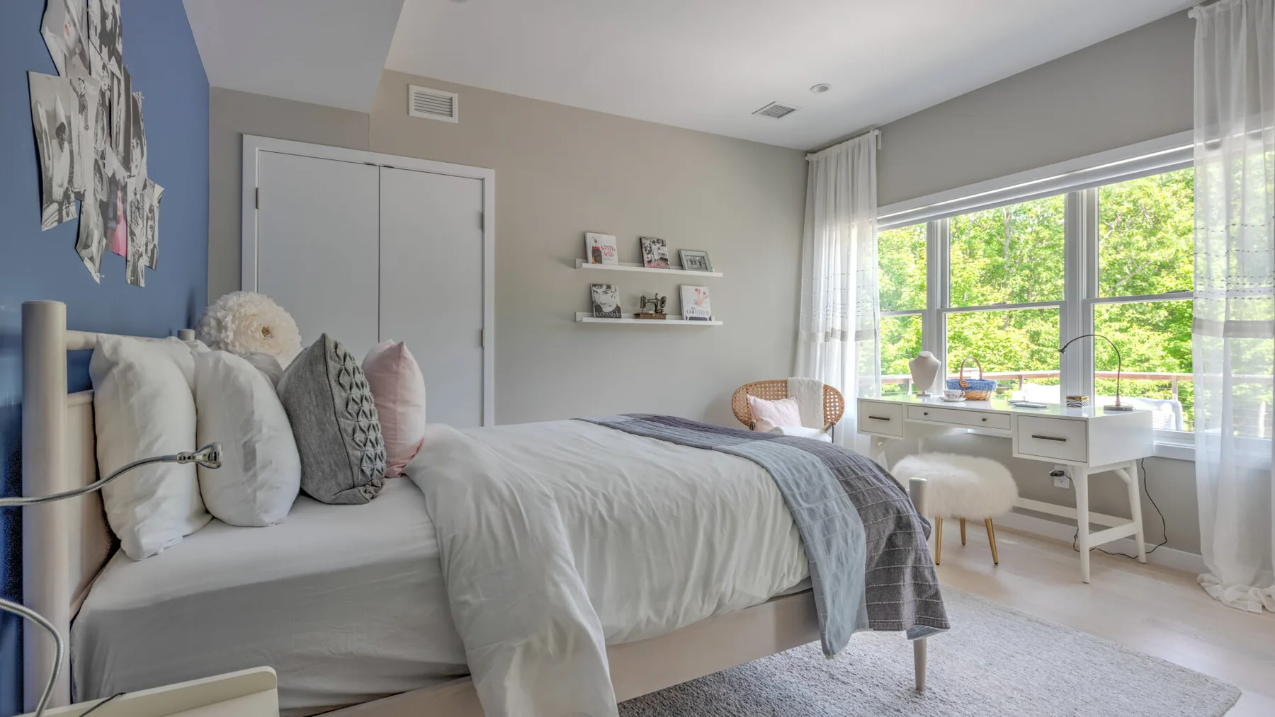 Un dormitorio luminoso con una cama junto a un escritorio y grandes ventanas.