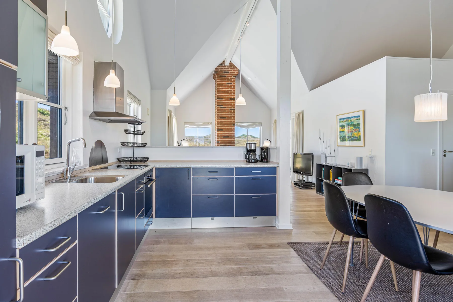 Una cocina abierta al comedor, con gabinetes azul oscuro y una mesa de comedor.
