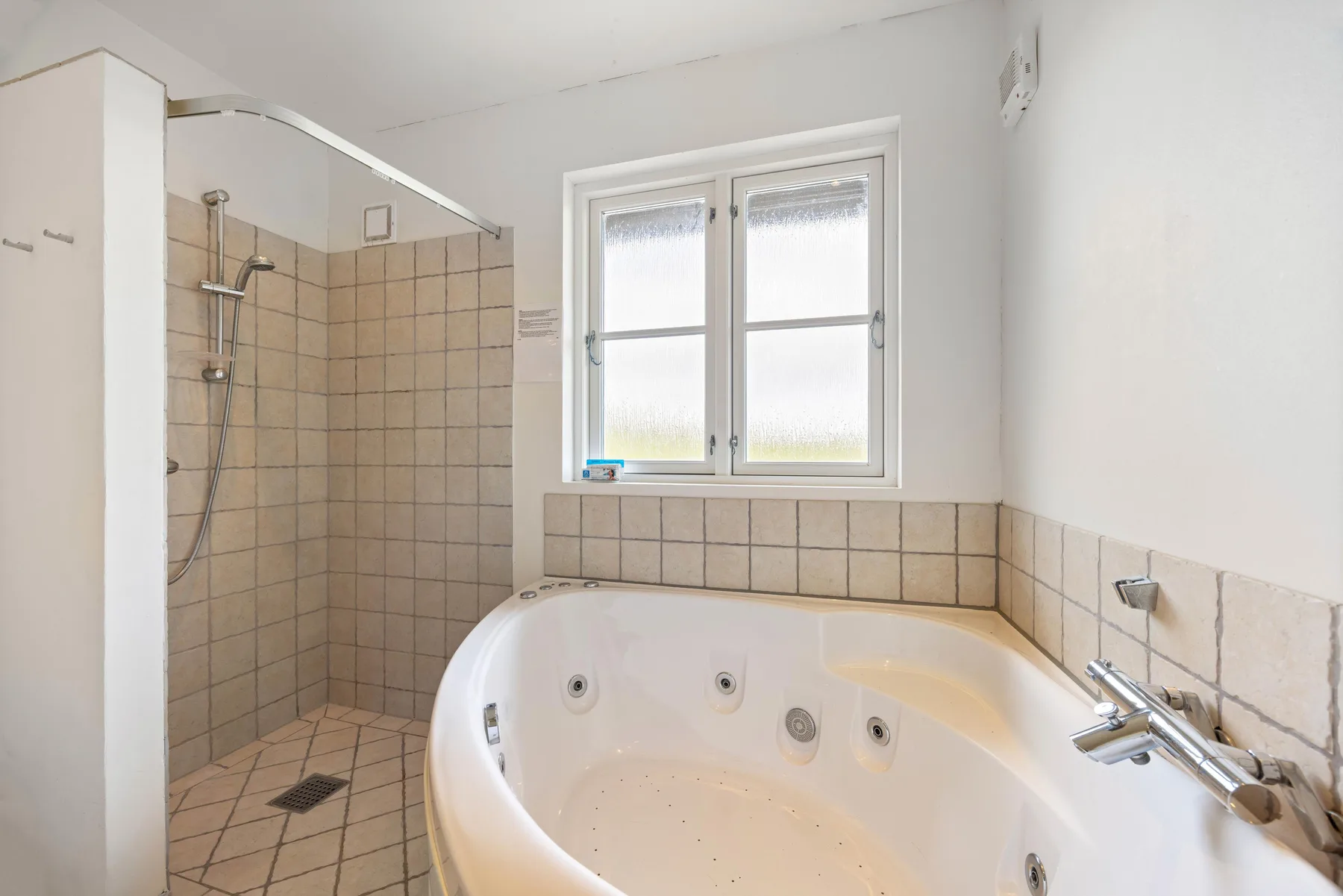 Un baño con bañera, ducha y ventana.