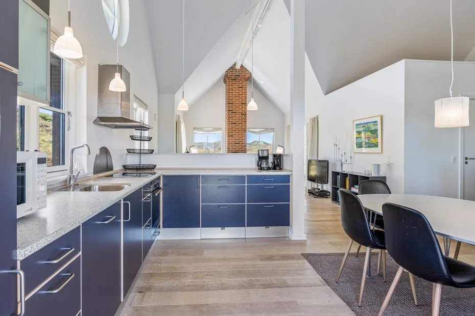 Una cocina y comedor luminosos, con gabinetes azul oscuro y una mesa larga.