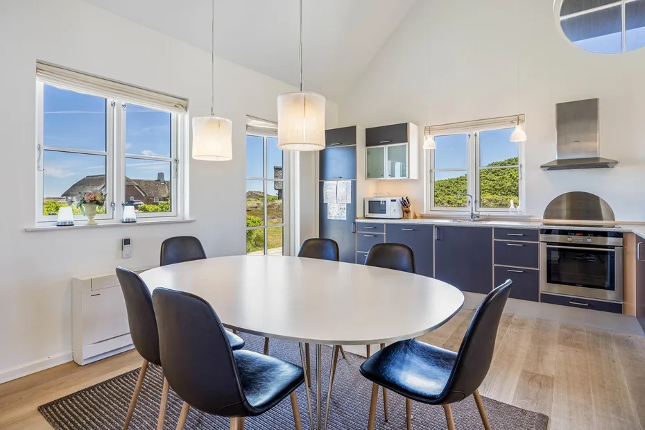 Una luminosa cocina con comedor, una mesa grande y ventanas.