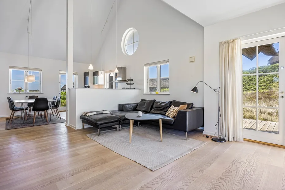 Una sala luminosa con un sofá seccional y puertas de vidrio grandes.