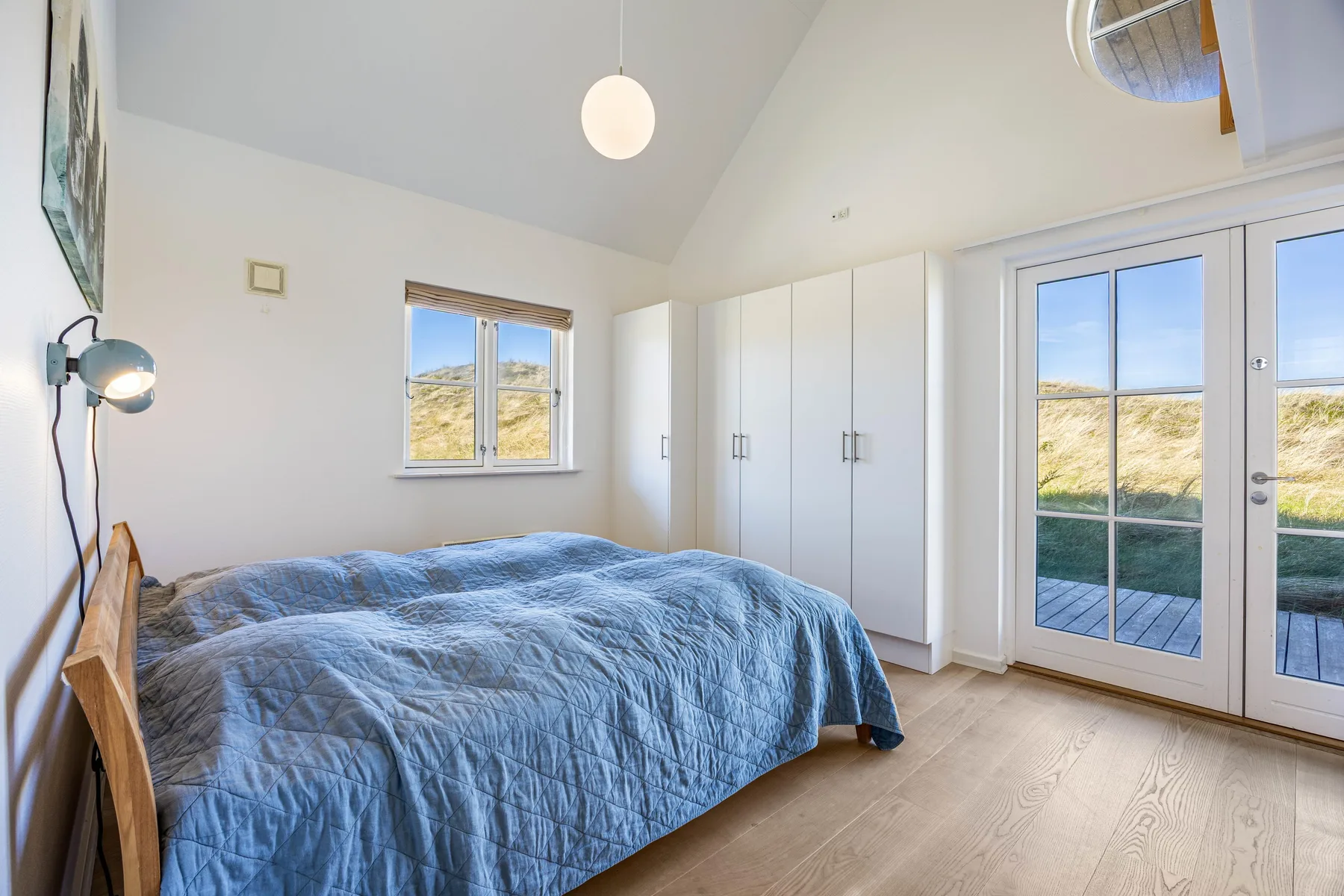 Un dormitorio luminoso con una cama, armarios empotrados y puertas de vidrio que dan a un patio.