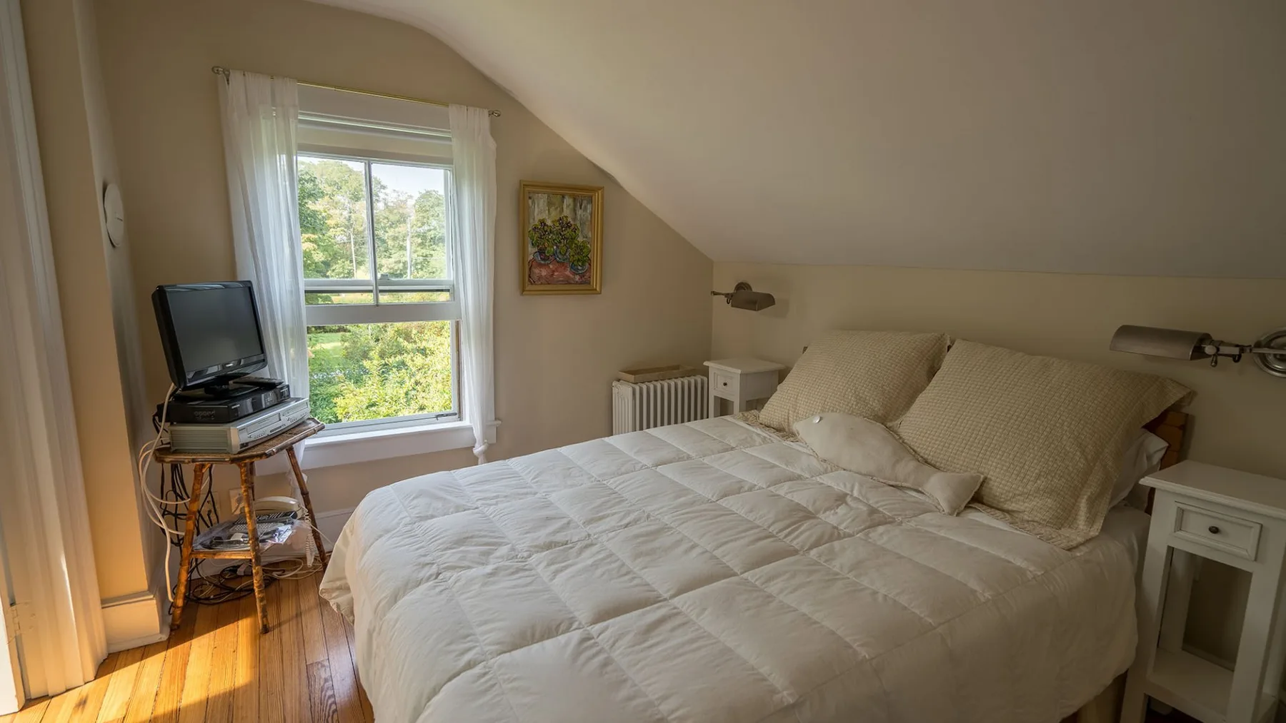 Un dormitorio con una cama bajo un techo inclinado y una ventana.