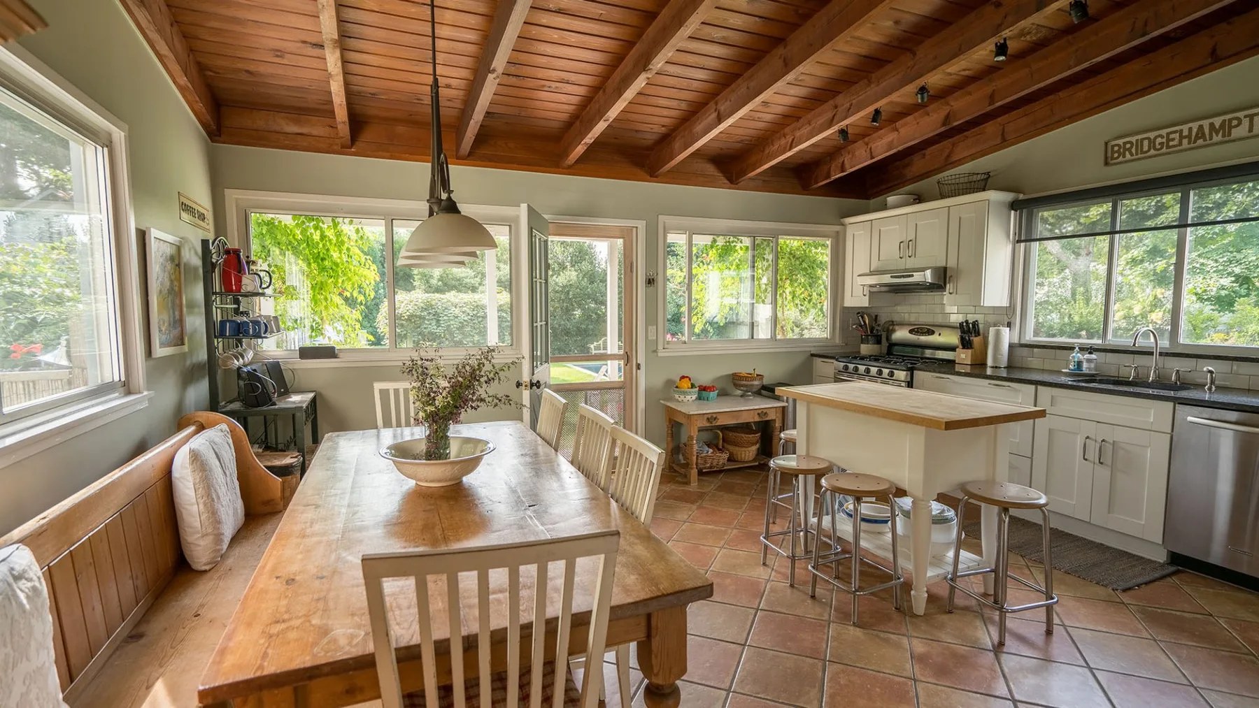 Una cocina y comedor luminosos con una mesa de madera bajo un techo de vigas.