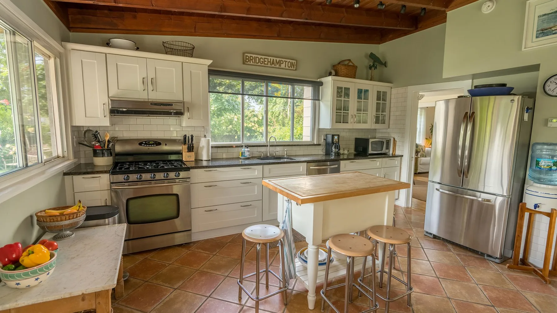 Una cocina luminosa con gabinetes blancos, electrodomésticos de acero inoxidable y una isla central.