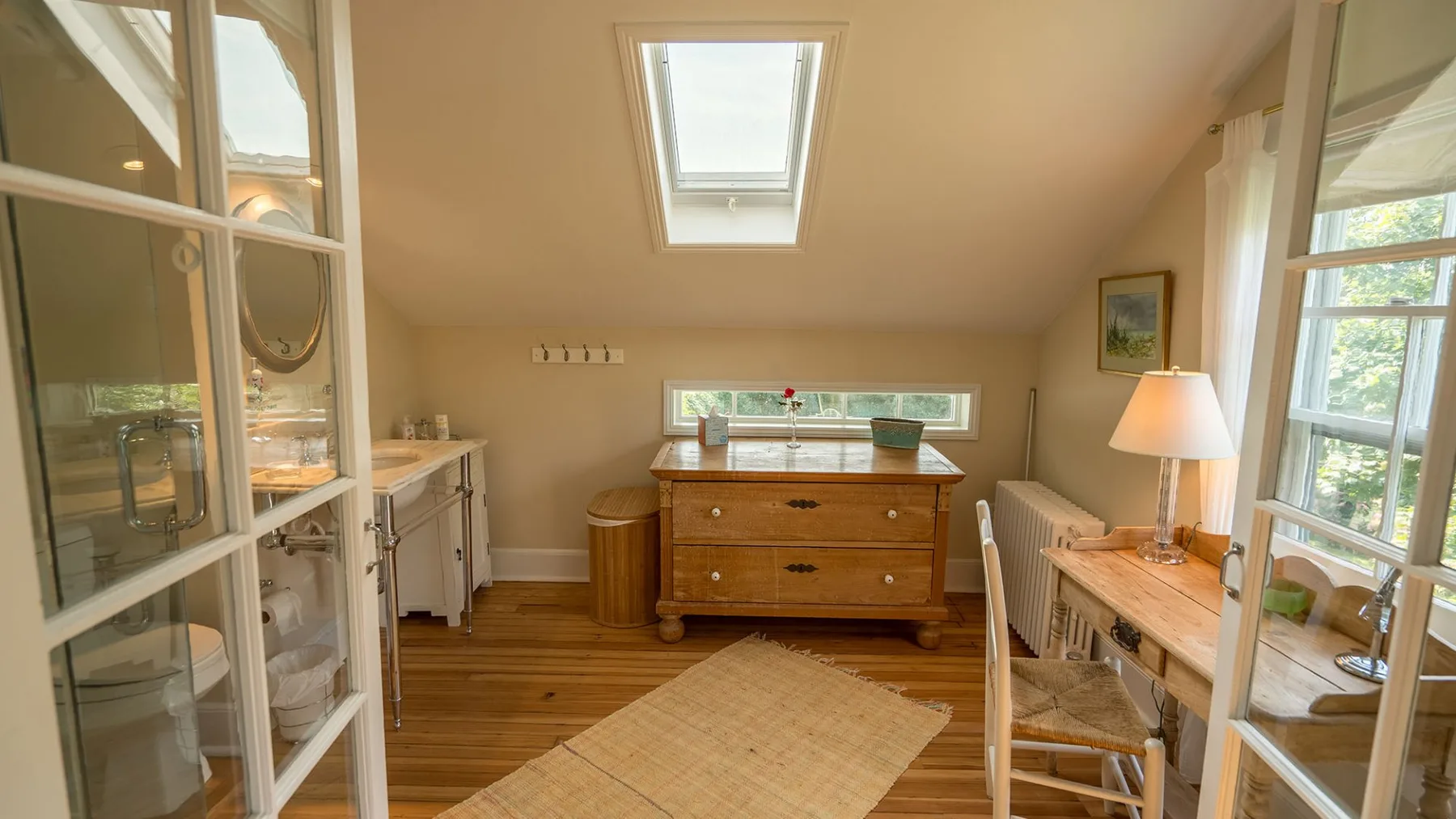Un dormitorio abuhardillado luminoso con cama de madera, escritorio y claraboya.
