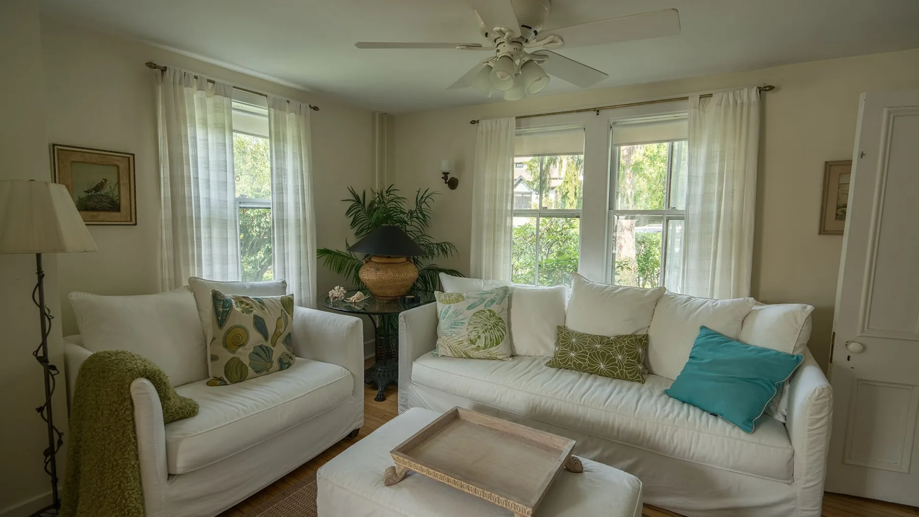 Una sala luminosa con asientos blancos, ventanas grandes y una mesa de centro.