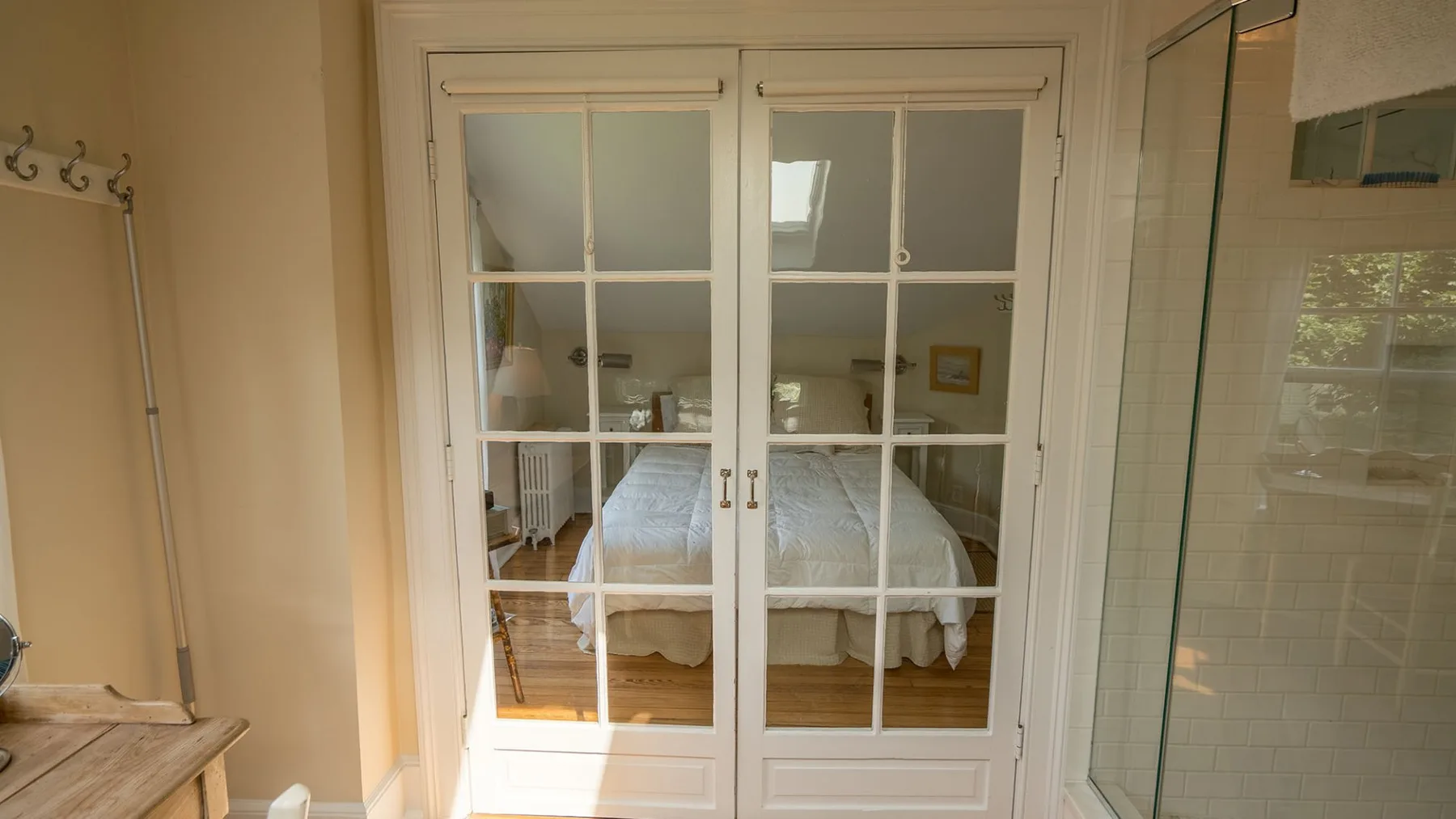 Se ve un dormitorio a través de puertas blancas con paneles de vidrio.