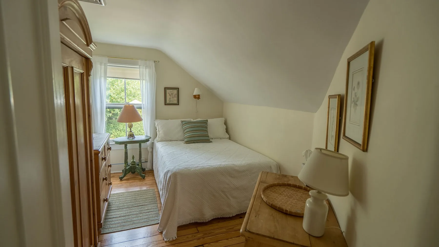 Un dormitorio con una cama bajo un techo inclinado y una ventana.