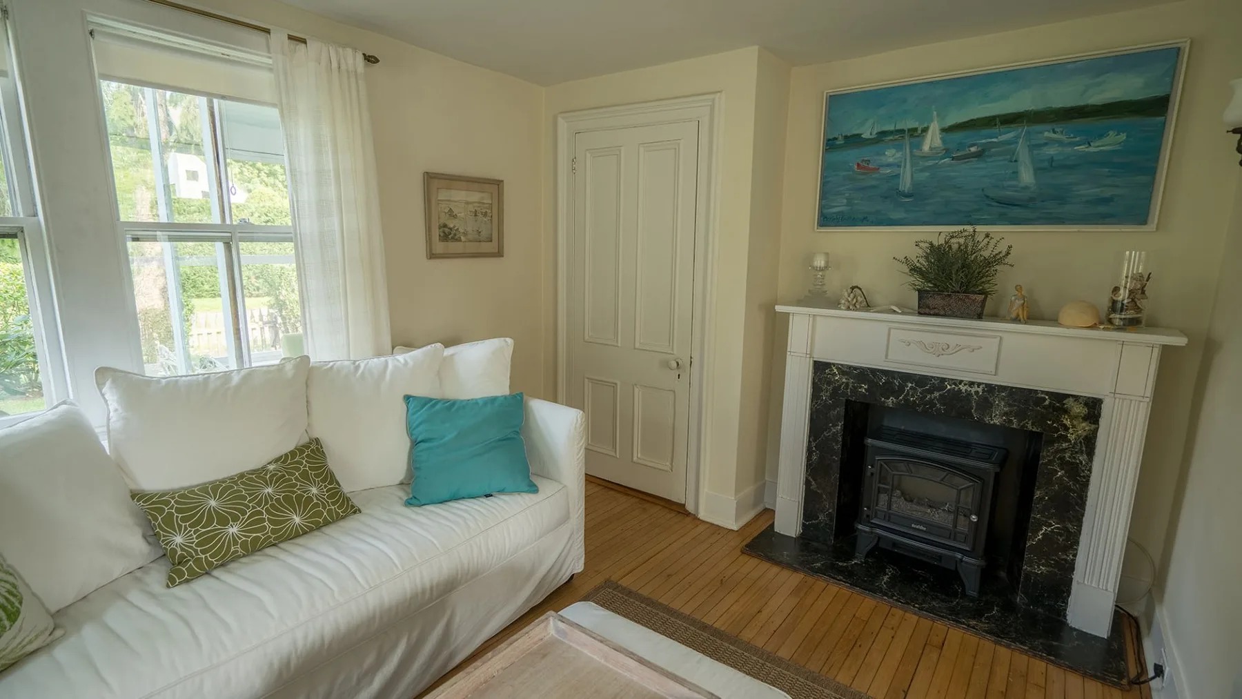 Una sala luminosa con asientos blancos junto a una chimenea y grandes ventanas.