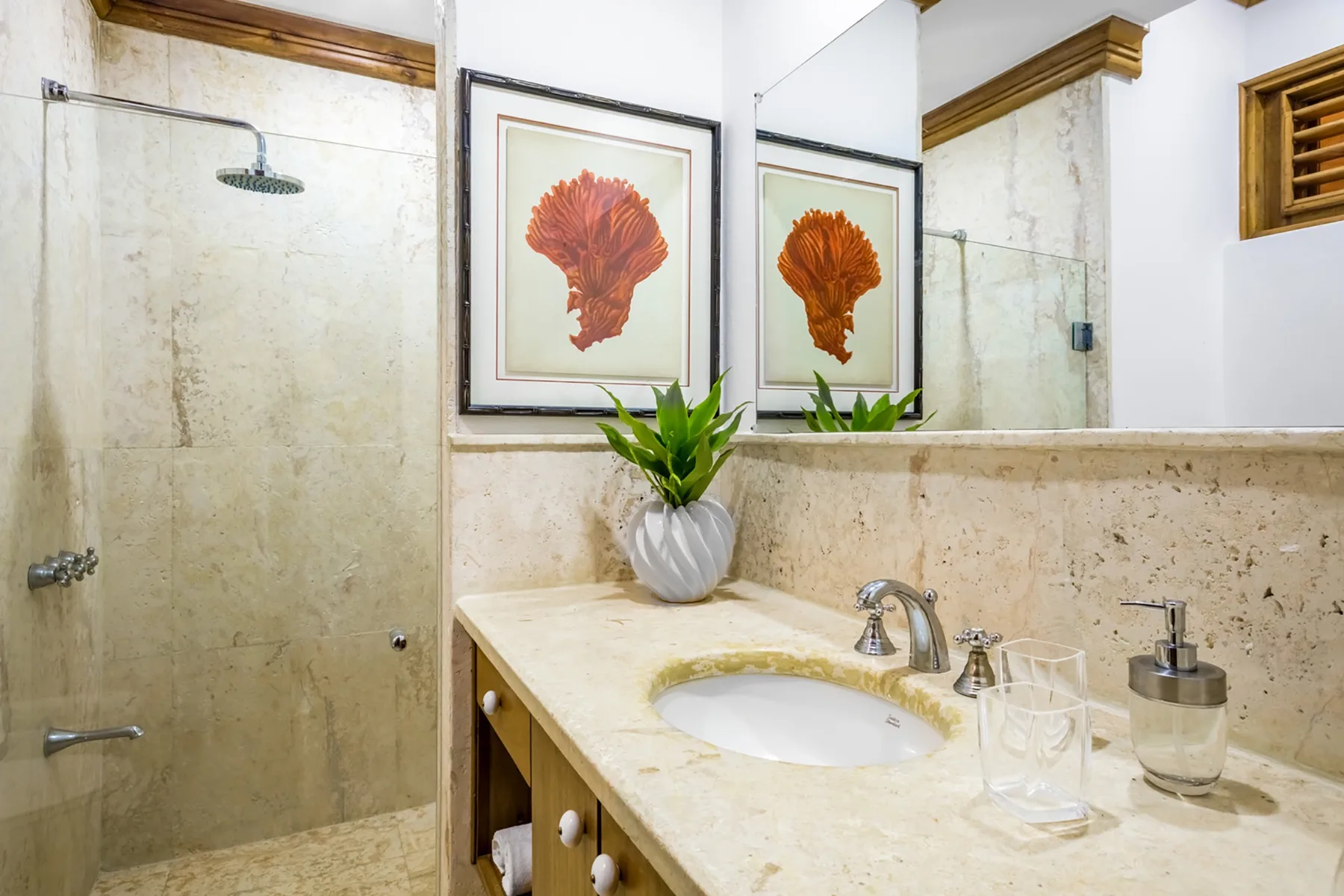 Un lavabo de baño con un fregadero y una lámina botánica enmarcada junto a la ducha.