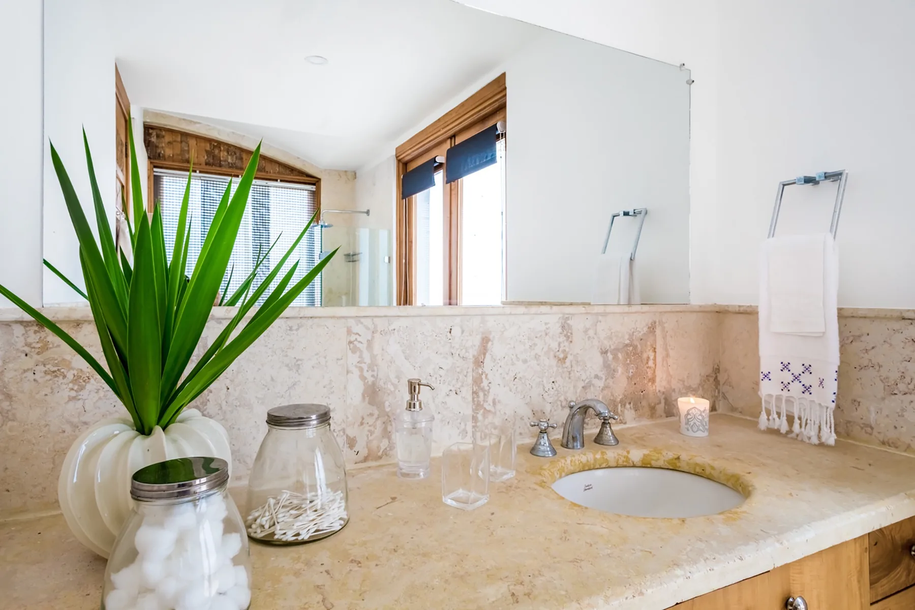 Un tocador de baño con lavabo, espejo grande y una planta en maceta.