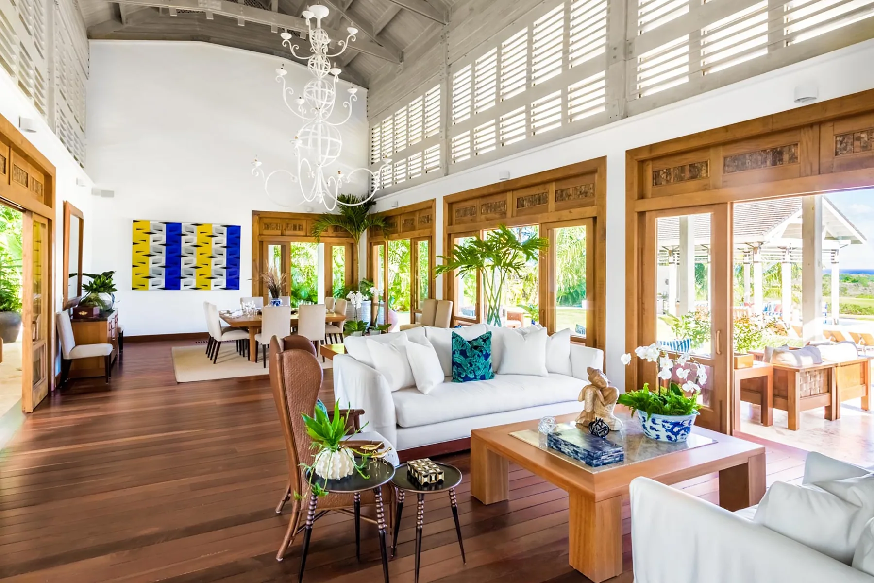 Una luminosa sala de estar y comedor con asientos, una mesa de madera y grandes ventanas.