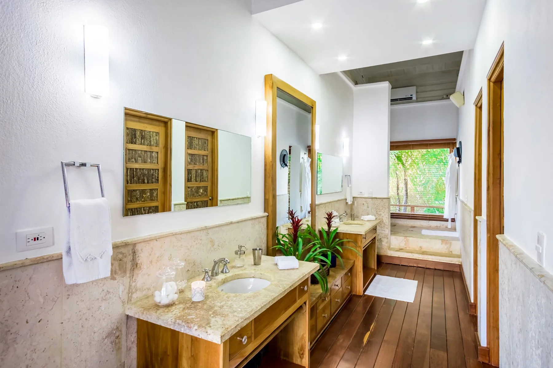 Un baño luminoso con un lavabo, una encimera larga y una ventana al fondo.